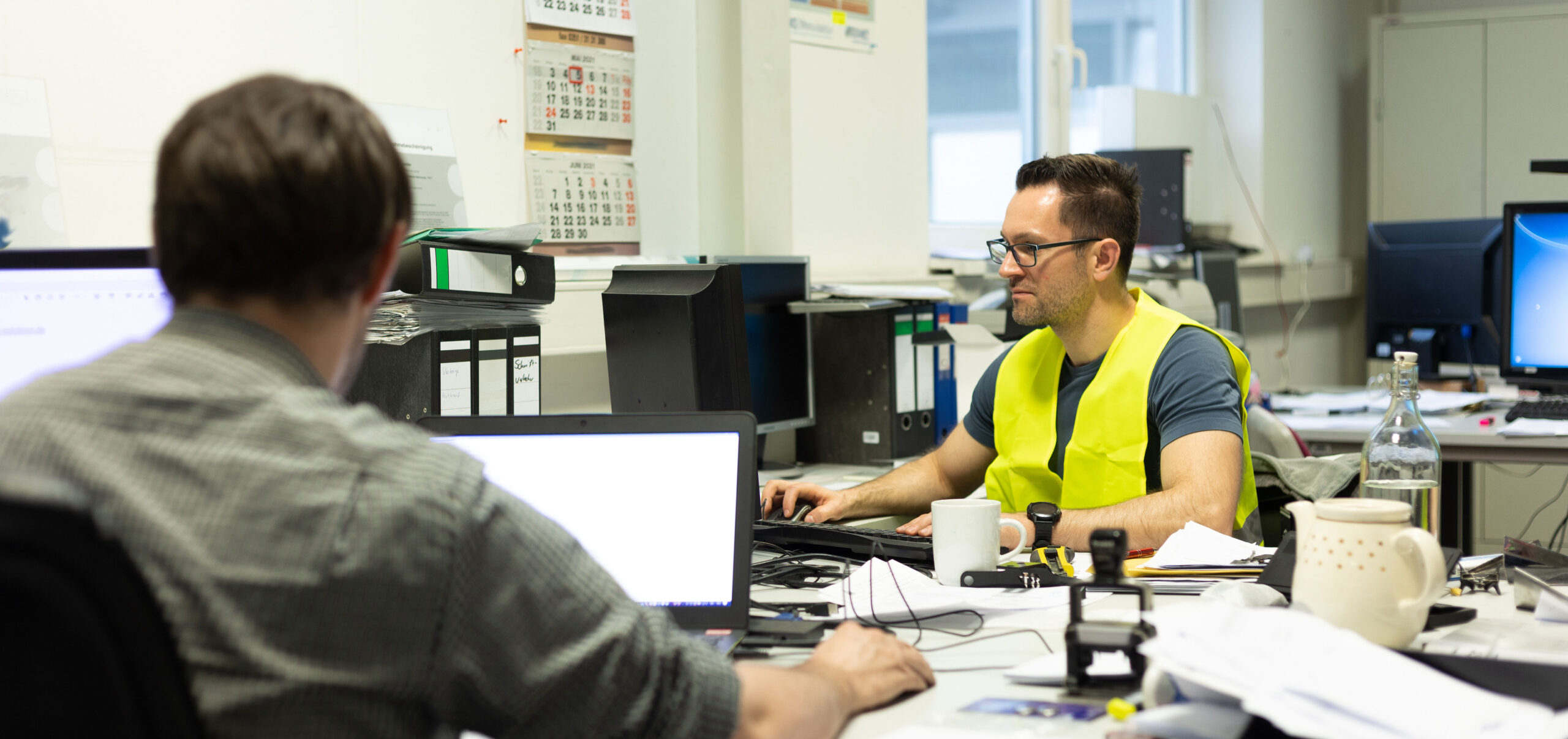 Büroarbeit - Mehrere Mitarbeiter arbeiten am Schreibtisch vor ihren PC's